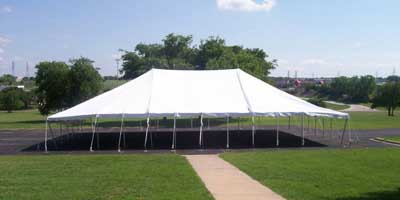 40x100 white top event rental tent staked in grass.